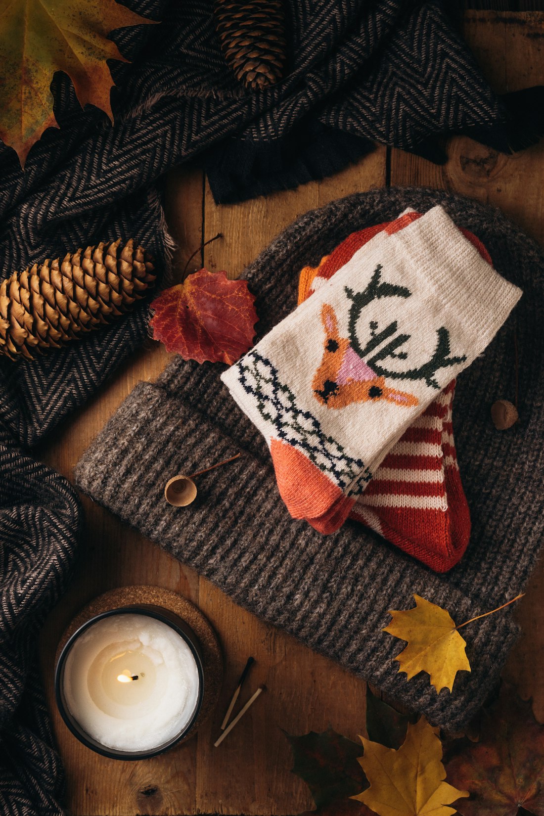 A knitted scarf and a lit candle on a table