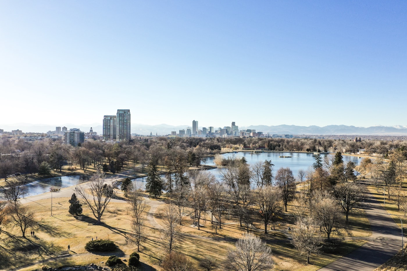 Denver skyline and City Park lake with the Rocky Mountains behind